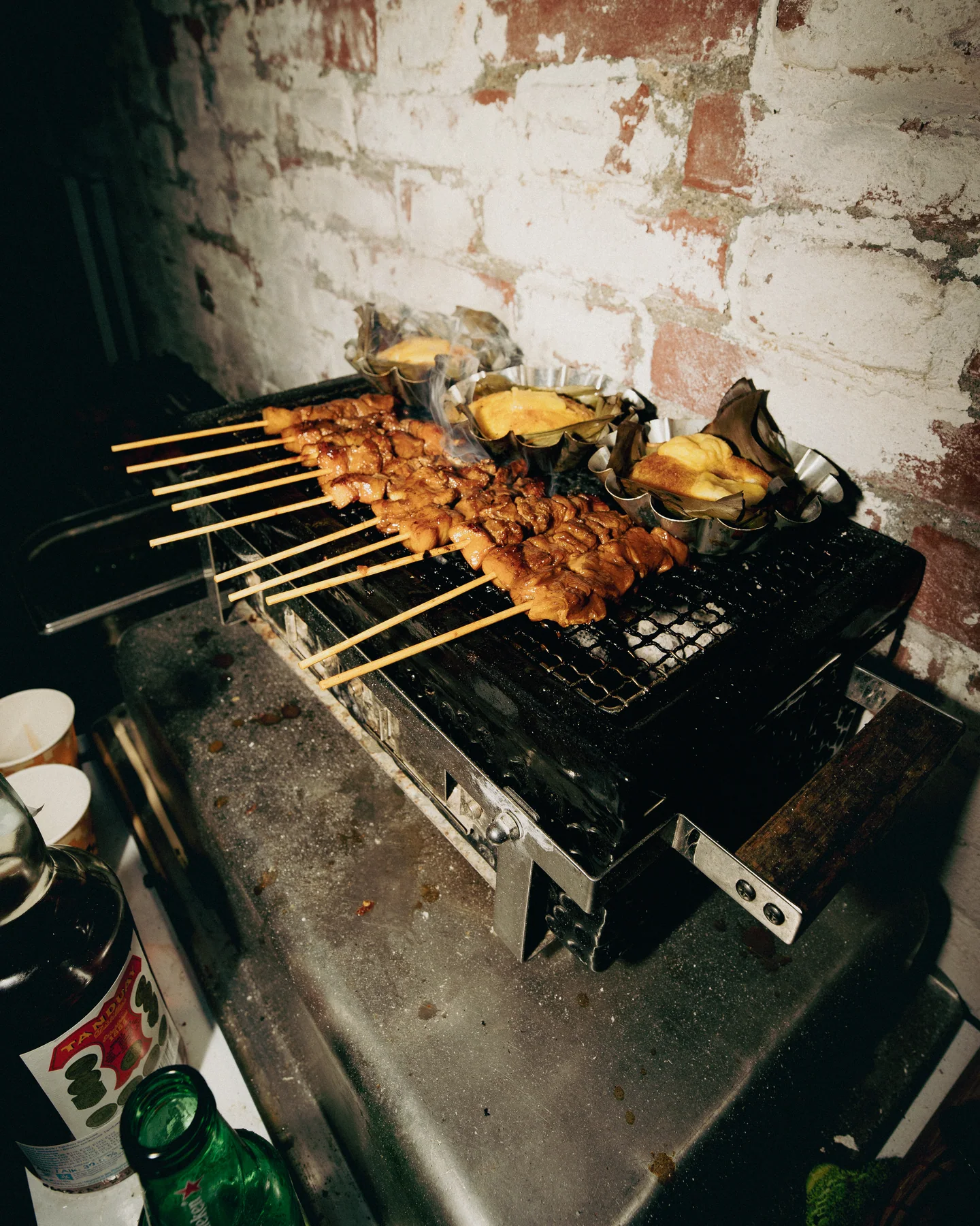 Skewers and vegetables cooking on a barbecue grill at TAYO Community BBQ