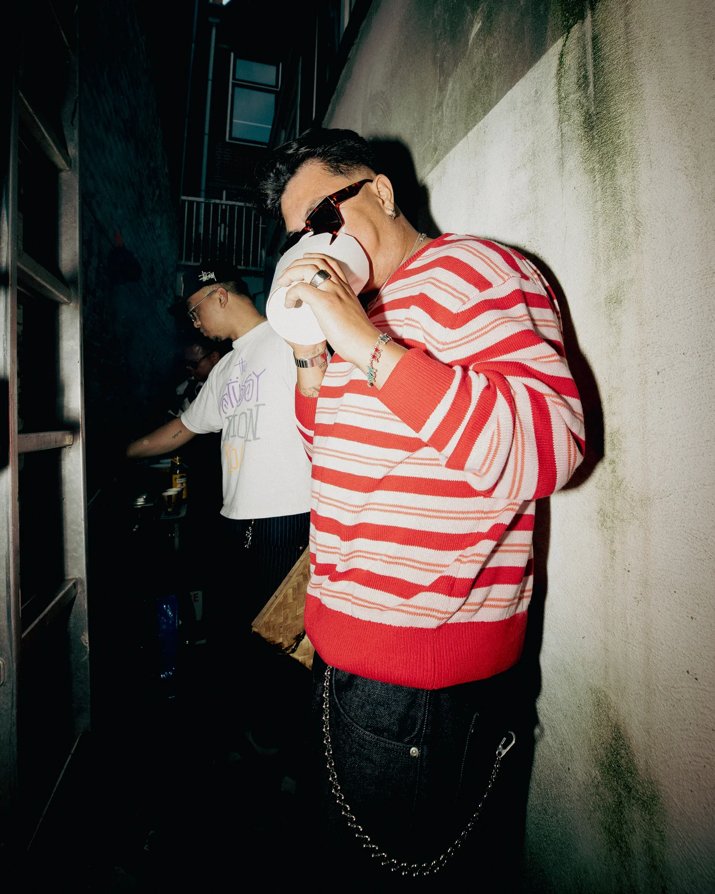 Guest drinking beside a brick wall at TAYO Community BBQ
