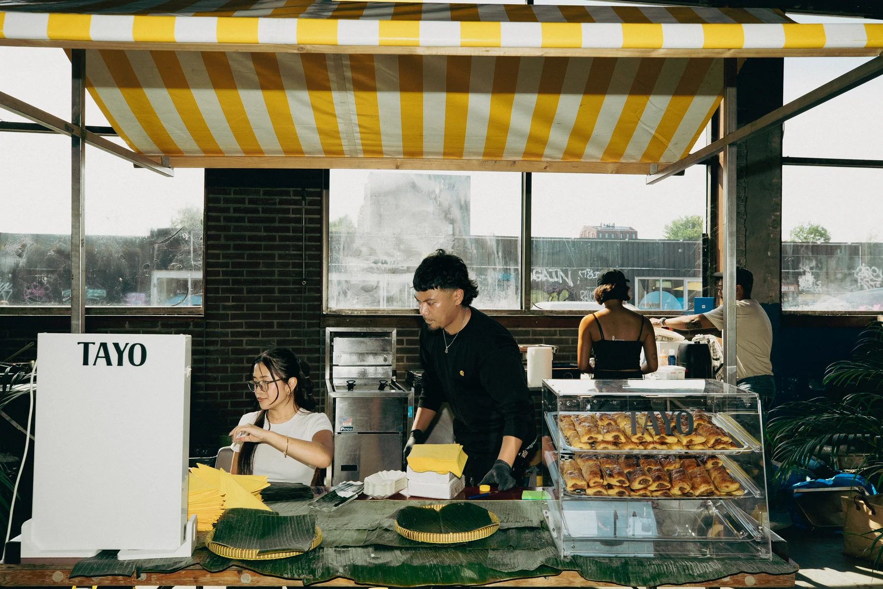 Food stall beneath a yellow and white striped canopy at Hapjesfestijn 2025