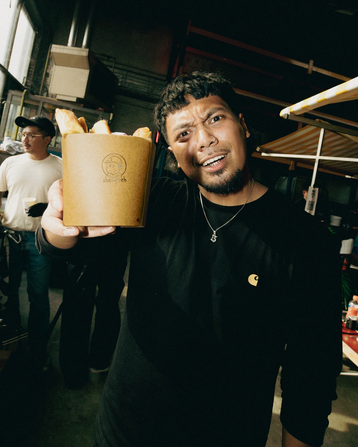Guest holding a paper cup beside the stall at Hapjesfestijn 2025